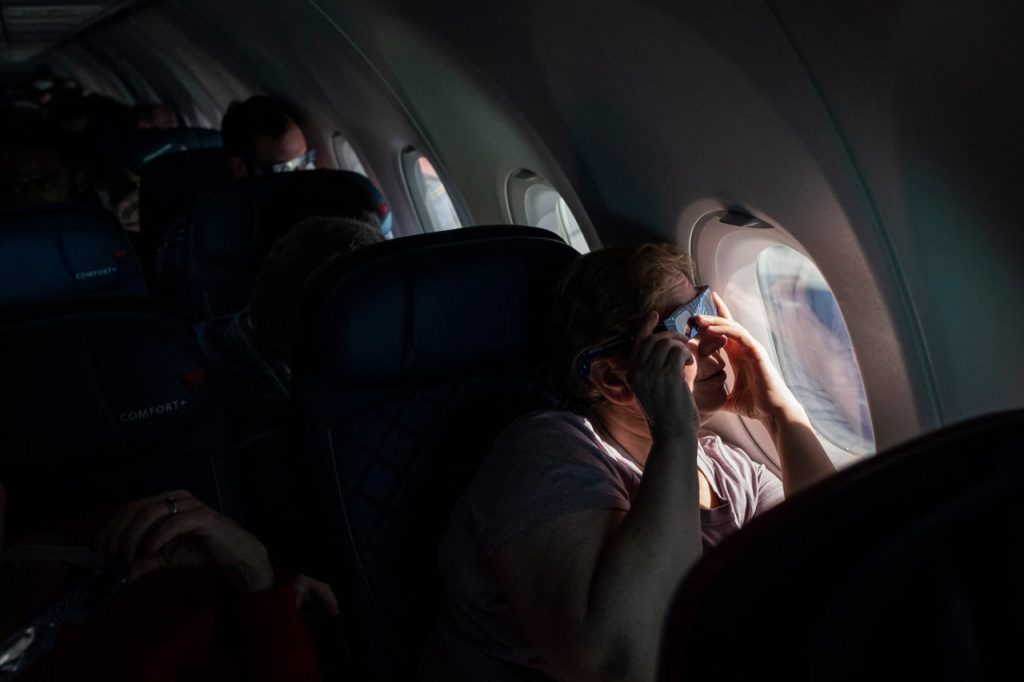 Kate Shamblott watches a solar eclipse through the window on Delta Air Lines Flight 1010
